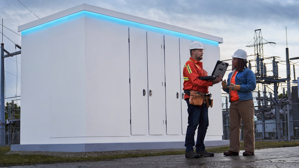 Two workers in front of an energy storage unit