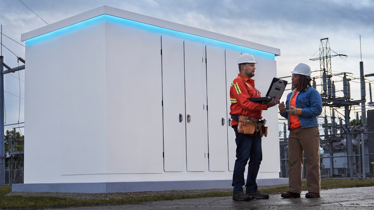 Two workers in front of an energy storage unit