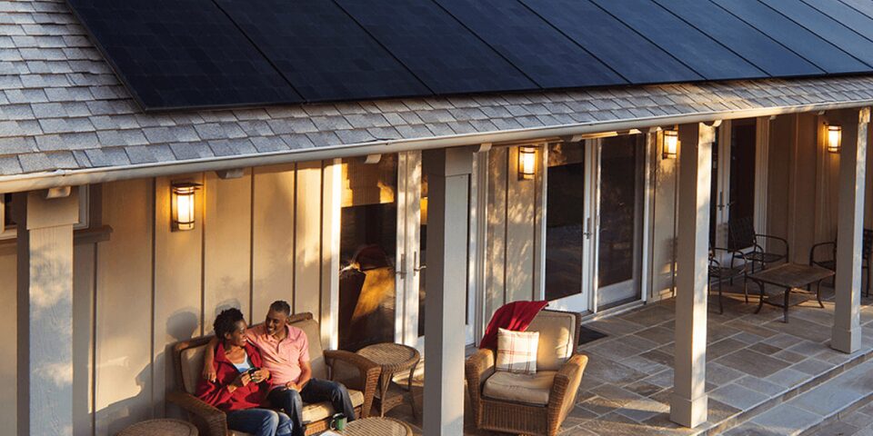 A couple sitting on their back deck enjoying their morning coffee, also in view are solar panels on their roof.