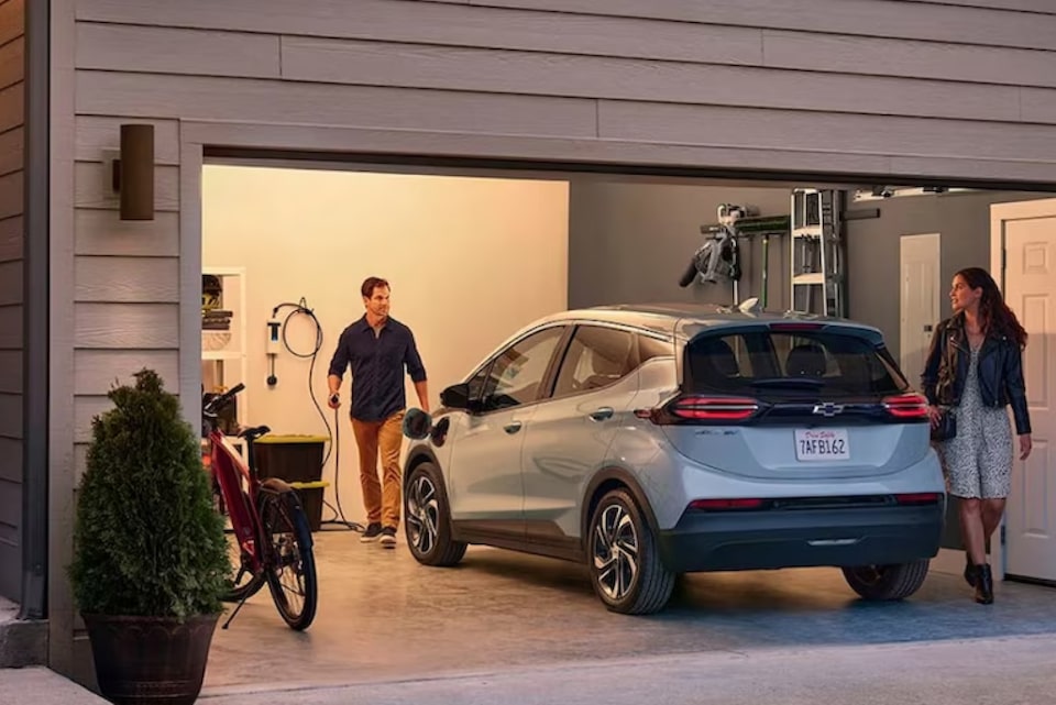 A man and woman charging their electric vehicle in a garage