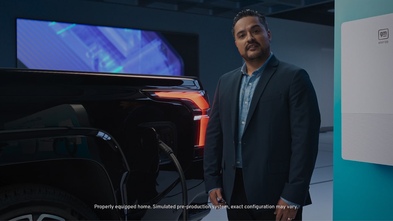 Man in front of a black EV with charger attached