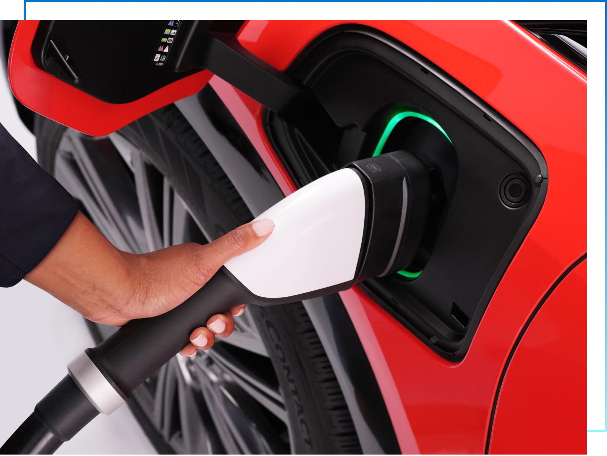 Hand holds public EV charger plugged into red GM EV