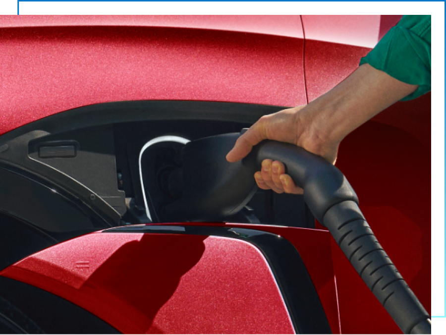 Hand holds public EV charger plugged into red GM EV