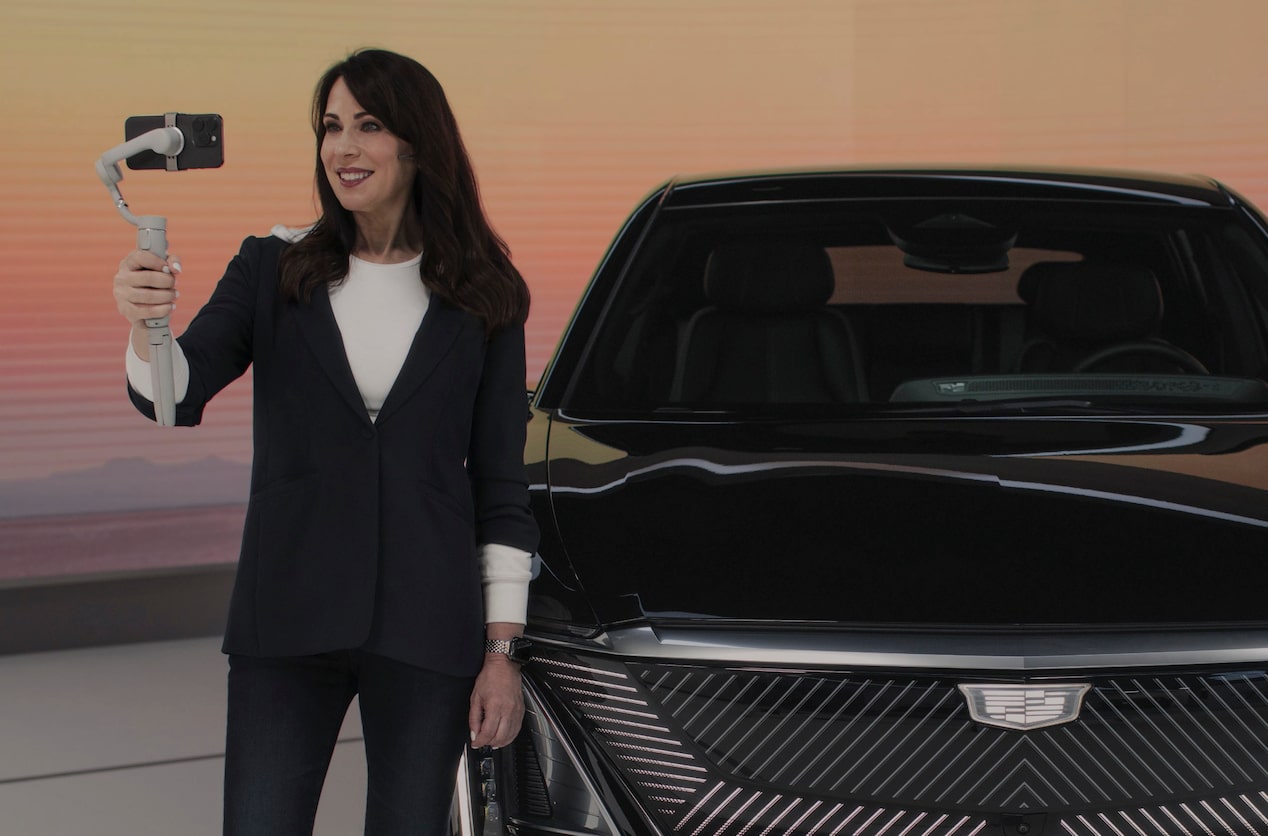 A woman is standing infront of a Cadillac LYRIQ EV and communicating with a user over the Energy LIVE digital platform.