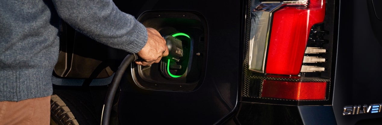 Someone's hand plugging charger into electric vehicle