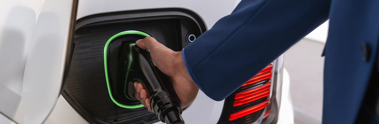 Someone's hand plugging charger into electric vehicle
