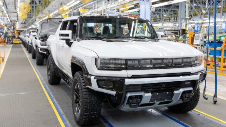 A factory line of white Hummer Evs in a well-lit factory.