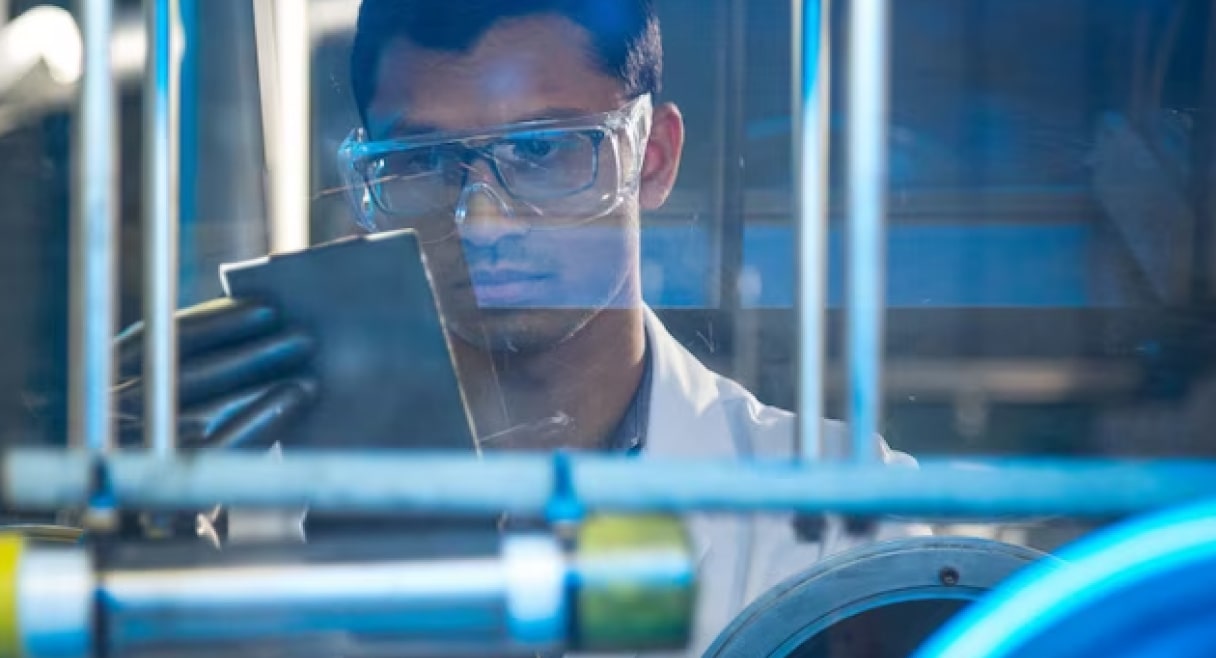 A scientist in lab coat and goggles