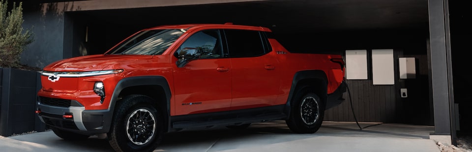 Red Chevrolet Silverado EV parked in garage with V2H charging equipment